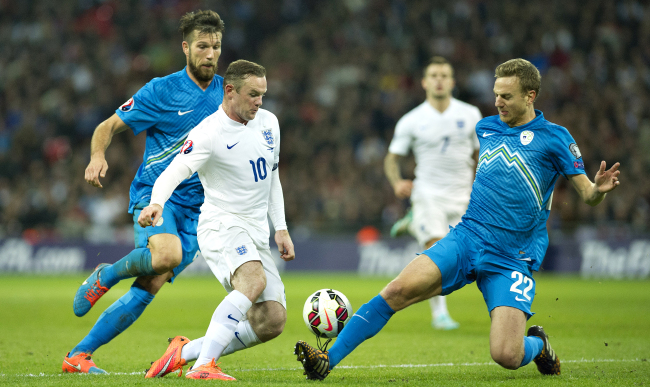 England’s Wayne Rooney (10) and Slovenia’s Boston Cesar (right) vie for the ball on Saturday.   AP-Yonhap