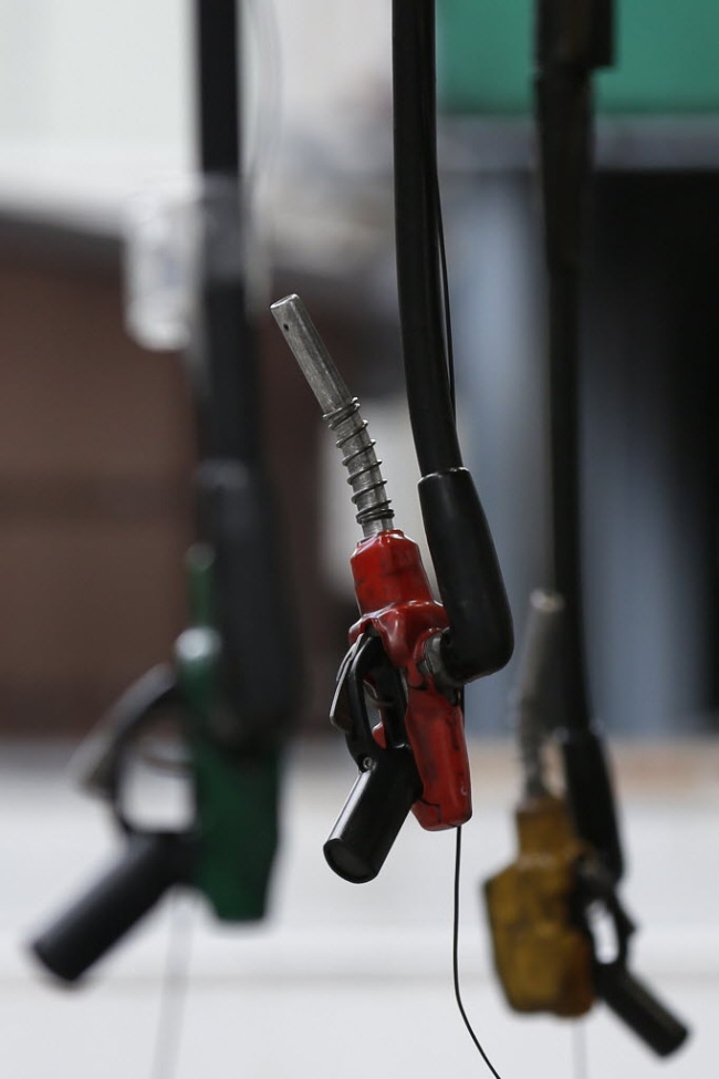 Fuel pumps hang at a gas station in Tokyo.   Bloomberg