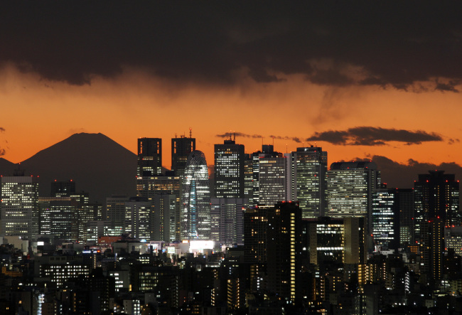 The sun sets behind buildings in Tokyo.    Bloomberg
