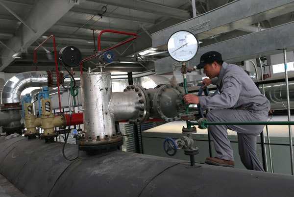 A worker examines equipment in a gas-fired plant in Beijing. Traditional coal-fired plants are switching to natural gas to generate power and supply heat for households from November in the capital. Xuan Jun/China Daily
