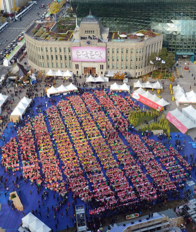 Thousands of people join in an event Friday to make 260 tons of kimchi for underprivileged people.   Yonhap