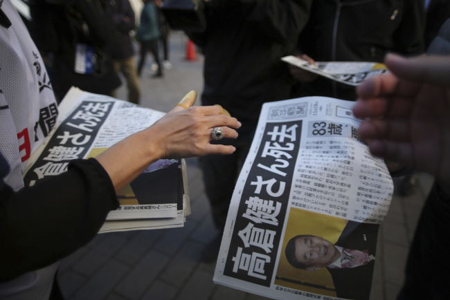 A worker distributes an extra edition of a newspaper with front page featuring an obituary notice of acclaimed Japanese film star Ken Takakura at Shimbashi Station in Tokyo, Tuesday.   AP-Yonhap