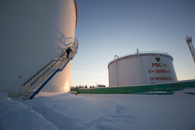 A worker climbs an access ladder outside an oil storage tank at the custody transfer facility in the Salym Petroleum Development oil fields in Salym, Russia.    Bloomberg