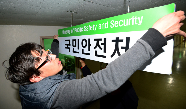An official puts up a signboard to mark the launch of the Ministry of Public Safety and Security at the Government Complex Building in Seoul on Wednesday.   Kim Myung-sub/The Korea Herald