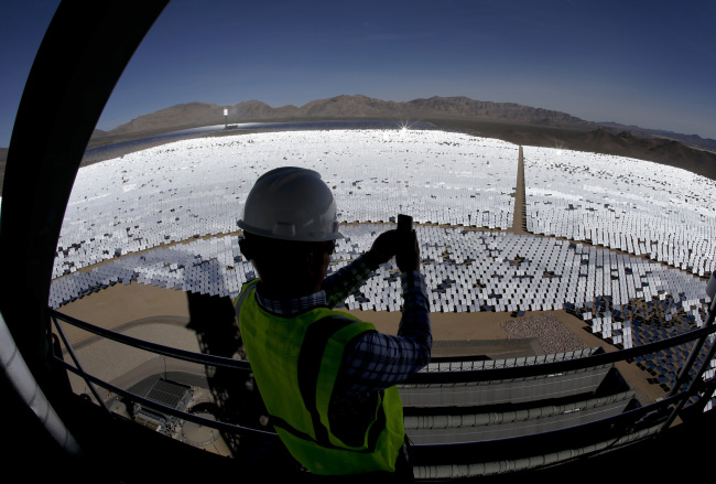 Jeff Holland takes a picture of some of the 300,000 computer-controlled mirrors that reflect sunlight to boilers that sit on 150-meter towers at the Ivanpah Solar Electric Generating site in Primm, Nevada.   (AP-Yonhap)