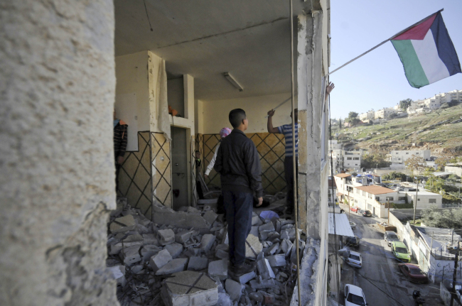 Palestinians hang a national flag inside the demolished apartment of Abdelrahman Shaludi in east Jerusalem on Wednesday.   AP-Yonhap