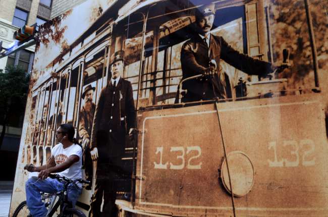 A man sitting on his bike is dwarfed by a mural in downtown San Antonio, Texas, several blocks from the Alamo on Sept. 16. (Los Angeles Times/TCA)