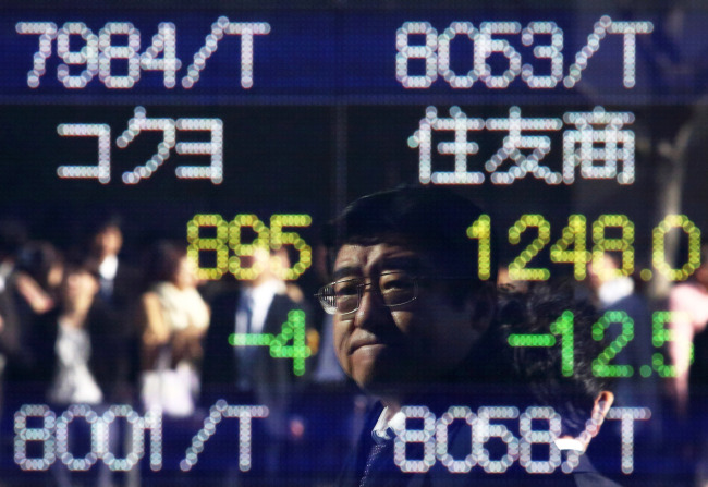 Pedestrians are reflected in an electronic stock board outside a securities firm in Tokyo, Japan, on Wedneday, Nov. 19, 2014. Japan's Topix index rose after Prime Minister Shinzo Abe postponed a planned sales-tax increase, called a snap election and ordered his ministers to start preparing a stimulus package. Photographer: Tomohiro Ohsumi/Bloomberg
Pedestrians are reflected in an electronic stock board outside a securities firm in Tokyo.   Bloomberg