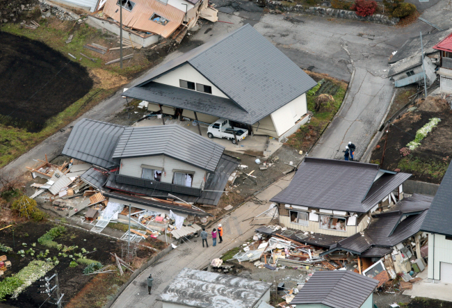 People view the damage on Sunday after a strong earthquake hit Hakuba, Nagano prefecture, central Japan, the night before, destroying more than half a dozen homes in the ski resort town and injuring at least 30 people. (AP-Yonhap)