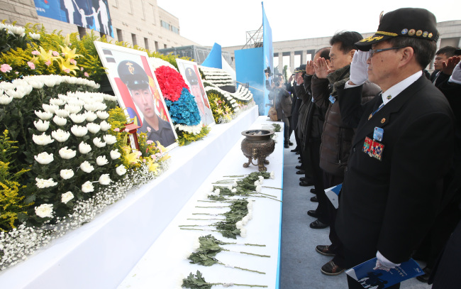 Citizens salute the photos of two marines killed in North Korea’s artillery attack in 2010 on Yeonpyeongdo Island during a ceremony marking the fourth anniversary of the provocation at the War Memorial of Korea in central Seoul on Sunday.   Yonhap