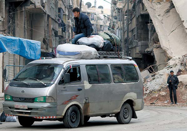A minibus passes a destroyed building in a rebel-controlled area in the northern Syrian city of Aleppo on Nov. 20. (AFP-Yonhap)
