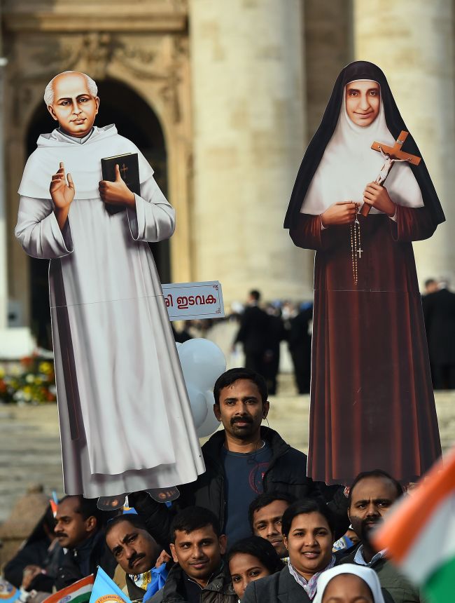 An Indian pilgrim holds cardboard cutouts prior to a canonization Mass for Indian Carmelite nun Euphrasia Eluvathingal (right) and Indian priest Kuriakose Elias Chavara (left) to be celebrated by Pope Francis at St. Peter’s Square at the Vatican on Sunday.   AFP-Yonhap