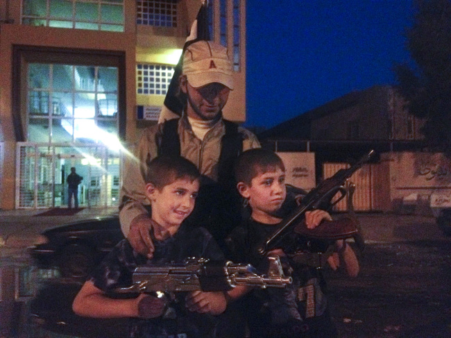 An Islamic militant group fighter stands with two children posing with weapons at the northern city of Mosul, Iraq, Saturday.   AP-Yonhap