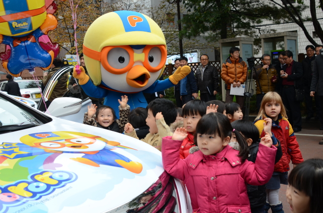 Children pose for a photo in front of a Pororo-themed taxi, which features the popular Korean cartoon character Pororo, in Seoul on Monday.   SMG