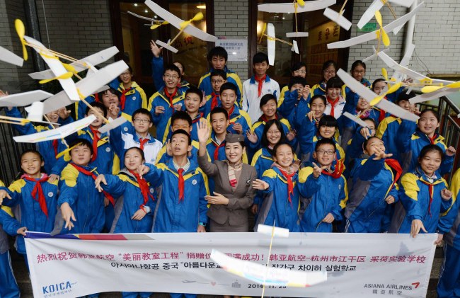 An Asiana flight attendant and students fly paper airplanes to celebrate the “sisterhood” between their school and the airline in Hangzhou, eastern China,  Tuesday.    Joint Airport Press Corps