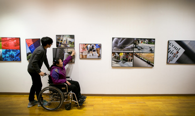 A female photographer reads braille text on a work in an exhibition of photographs by the visually impaired at Sangmyung Art Hall Gallery in Seoul.   Park Hyun-koo/The Korea Herald