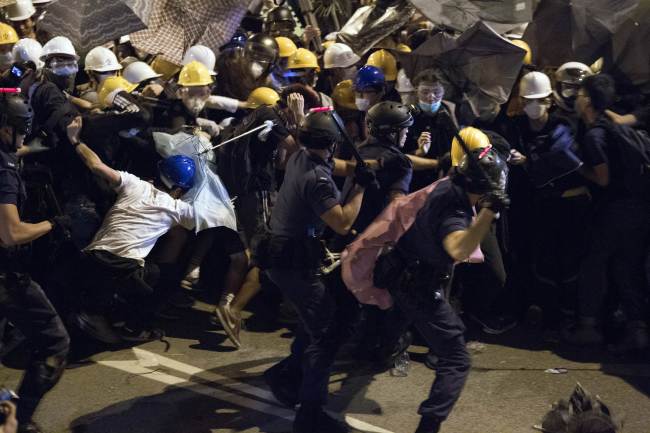 Police use batons against pro-democracy protesters near the government headquarters in the Admiralty district of Hong Kong on Monday.      AP-Yonhap