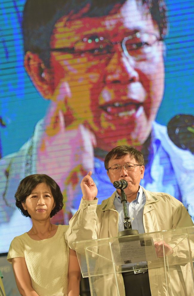Newly elected independent Taipei Mayor Ko Wen-je (right) speaks next to his wife Chen Pei-chi in front of a giant screen near his campaign headquarters in Taipei on Friday.   AFP-Yonhap