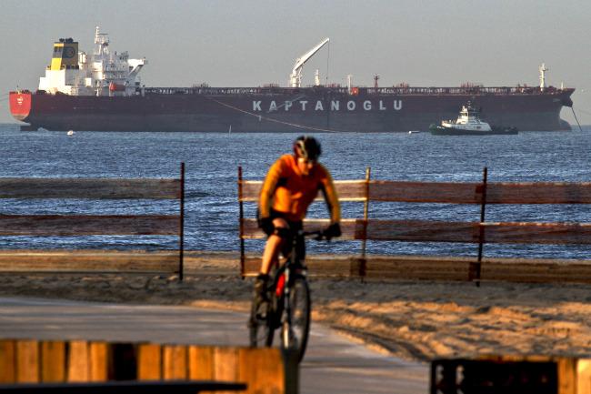 A cyclist rides past a Kaptanoglu Shipping oil tanker as it unloads a shipment of oil through an underwater pipeline connected to the Chevron El Segundo refinery in El Segundo, California.   Bloomberg