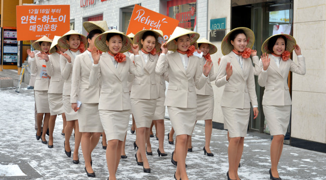 Jeju Air crew members walk down the street near the Hongik University subway station in Seoul on Wednesday, wearing Vietnam’s traditional hat to promote the company’s new air route between Incheon-Hanoi, which will open on Dec. 18.   Kim Myung-sub/The Korea Herald