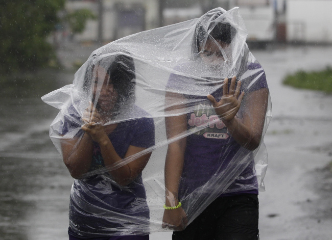Filipino residents use plastic sheets to protect themselves from wind and rain brought by Typhoon Hagupit in Legazpi, Albay province, eastern Philippines on Sunday. (Related story on Page 5)    AP-Yonhap