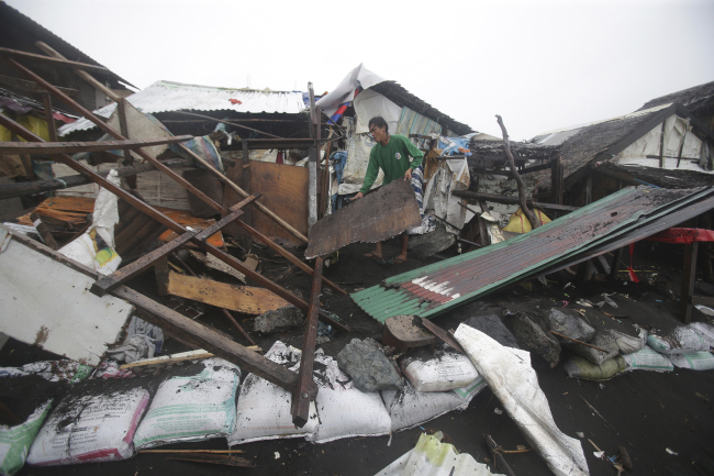 A Filipino man clears away debris from the remains of his damaged home as strong waves from Typhoon Hagupit battered a coastal village in Legazpi, Albay province, eastern Philippines, Monday.   AP-Yonhap