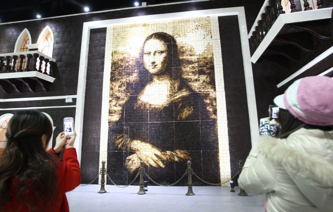 People take photos of a chocolate Mona Lisa painting in Shanghai on Jan. 18, 2013.   AFP-Yonhap