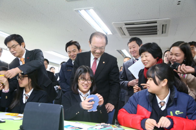 Education Minister Hwang Woo-yea (center, standing) speaks to a first-year middle school student at Seogwi Jungang Girls’ School in Jeju Island on Monday.   Ministry of Education