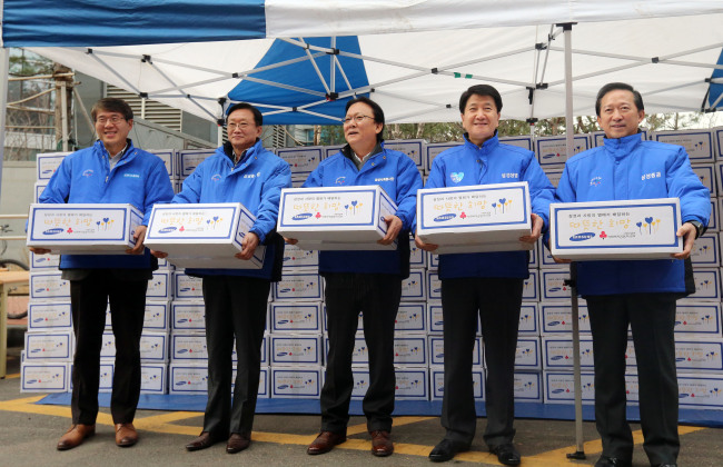 <YONHAP PHOTO-0530> 쪽방 봉사하는 삼성사회봉사단 (서울=연합뉴스) 최재구 기자 = 박근희 삼성사회봉사단 부회장(가운데) 등 삼성사장단이 10일 오전 서울 용산구 동자동 일대 쪽방을 방문해 선물을 전달하며 포토타임을 갖고 있다. 삼성사회봉사단 박근희 부회장 등 24명은 이날 서울 용산·남대문·종로·영등포 등 6군데 쪽방촌을 방문해 생필품과 선물을 전하고 몸이 불편한 이웃을 돌봤다. 왼쪽부터 박동건 삼성디스플레이, 박대영 삼성중공업, 박 부회장, 김창수 삼성생명, 윤용암 삼성증권 사장. 2014.12.10 jjaeck9@yna.co.kr/2014-12-10 11:40:25/ <저작권자 ⓒ 1980-2014 ㈜연합뉴스. 무단 전재 재배포 금지.>
Samsung executives pose for a photo ahead of delivering gifts to underprivileged people in Seoul. From left are: Samsung Display CEO Park Dong-gun; Samsung Heavy Industries CEO Park Dae-young; Samsung Corporate Citizenship vice chairman Park Keun-hee; Samsung Life Insurance CEO Kim Chang-soo; and Samsung Securities CEO Yoon Yong-am.   Park Hyun-koo/The Korea Herald