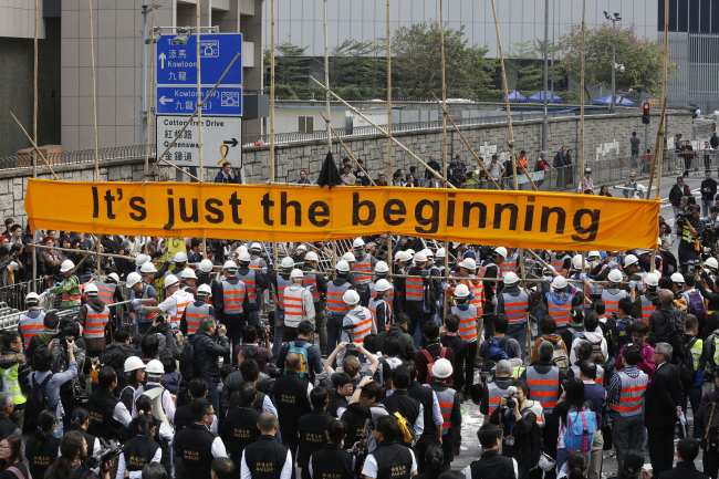 Workers clear barricades at the occupied area outside government headquarters in Hong Kong on Thursday.   AP-Yonhap