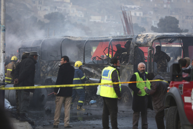 Afghan security guards inspect a damaged bus at the site of a suicide attack in Kabul on Saturday.   AP-Yonhap