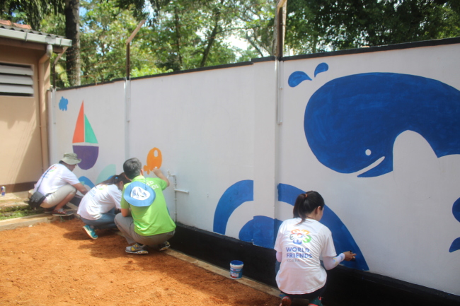 Volunteers and officials of the Korea International Cooperation Agency and reporters paint murals at Sujatha Vidyalaya, a girls’ elementary school in Matara, Sri Lanka.   KOICA