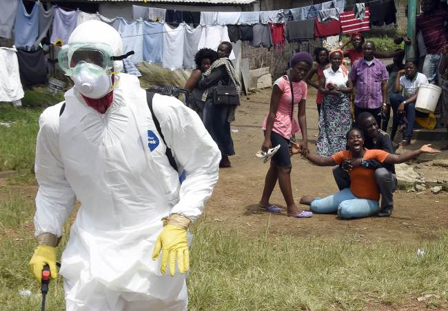 People look on as a woman reacts after her husband is suspected of dying from the Ebola virus in Monrovia, Liberia.   AFP-Yonhap