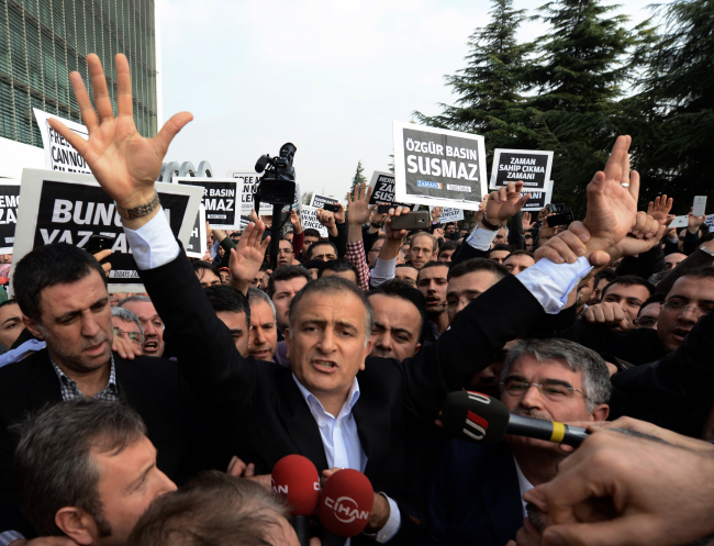 Ekrem Dumanli, editor-in-chief of Zaman newspaper, acknowledges cheering supporters as he is detained outside his office in Istanbul, Turkey, Sunday.   AP-Yonhap