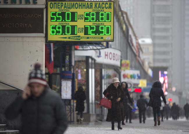 Pedestrians walk past an illuminated electronic neon sign displaying US dollar and Euro exchange rates outside a foreign exchange bureau in Moscow, Russia, on Friday, Dec. 12, 2014. The ruble tumbled to a record for a second day, spurring speculation Russia's central bank intervened to stem the rout, and bonds slid as weaker oil prices worsen the outlook for an economy verging on recession. Photographer: Alexander Zemlianichenko Jr./Bloomberg
Pedestrians walk past an electronic sign displaying currency exchange rates outside a foreign exchange bureau in Moscow on Friday.    Bloomberg