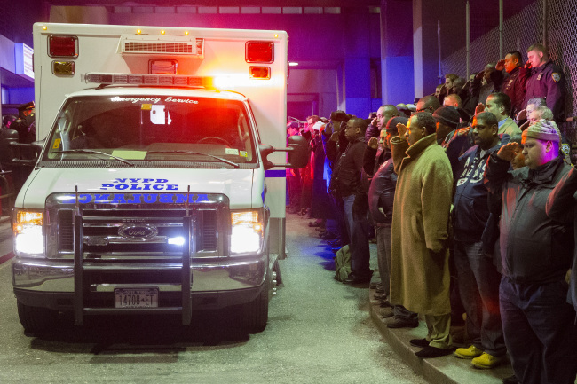 <YONHAP PHOTO-0622> Mourners stand at attention as the bodies of two fallen NYPD police officers are transported from Woodhull Medical Center, Saturday, Dec. 20, 2014, in New York. An armed man walked up to two New York Police Department officers sitting inside a patrol car and opened fire Saturday afternoon, killing one and critically wounding a second before running into a nearby subway station and committing suicide, police said. (AP Photo/John Minchillo)/2014-12-21 12:40:15/ <저작권자 ⓒ 1980-2014 ㈜연합뉴스. 무단 전재 재배포 금지.>
Mourners stand at attention as the bodies of two fallen New York Police Department officers are transported from Woodhull Medical Center in New York on Saturday. An armed man walked up to two officers sitting inside a patrol car and opened fire Saturday afternoon, killing both officers before running into a nearby subway station and committing suicide, police said. (Related story on Page 6)   AP-Yonhap