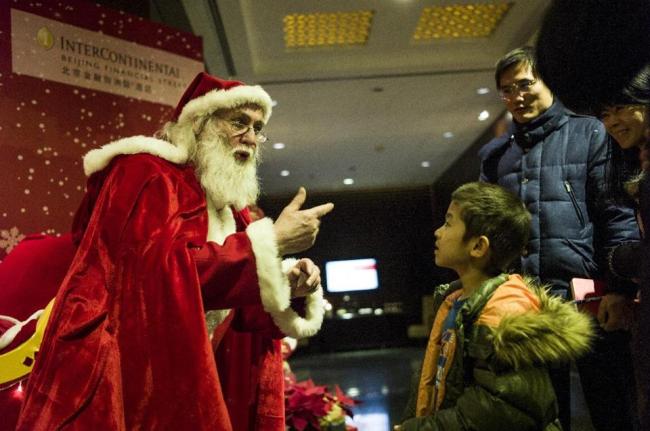 A Santa Claus tells a story to a boy at the Intercontinental hotel in Beijing.   AFP