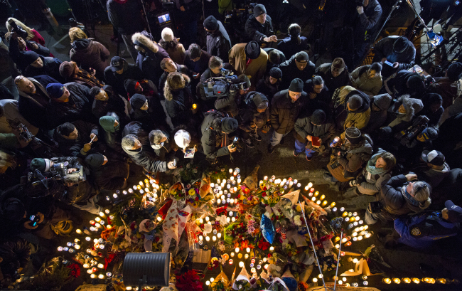 Mourners, members of the media and other gather at a memorial Sunday, near the spot where two New York Police Department officers, sitting inside a patrol car the previous day, were shot by an armed man, killing them both. (Related story on Page 6)   AP-Yonhap