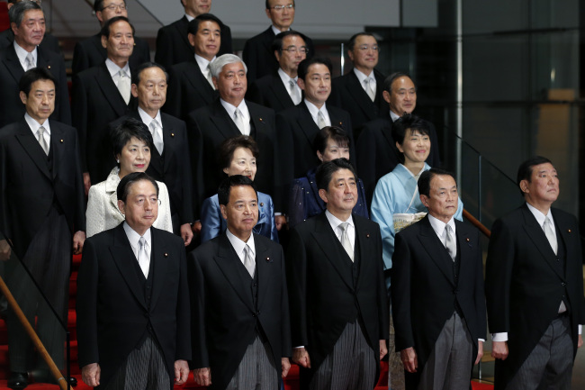 Shinzo Abe, Japan’s prime minister (front row, center), poses for a group photograph with his new cabinet members at his official residence in Tokyo, Japan, Wednesday.   Bloomberg