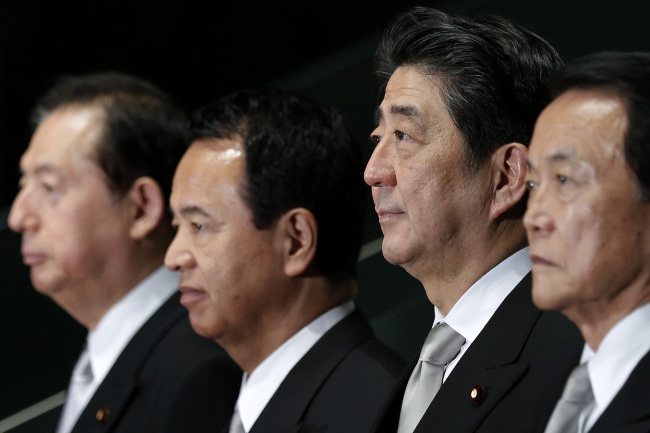 Japan’s Prime Minister Shinzo Abe (second from right) poses for a group photograph with members of his new cabinet in Tokyo on Wednesday.    Bloomberg