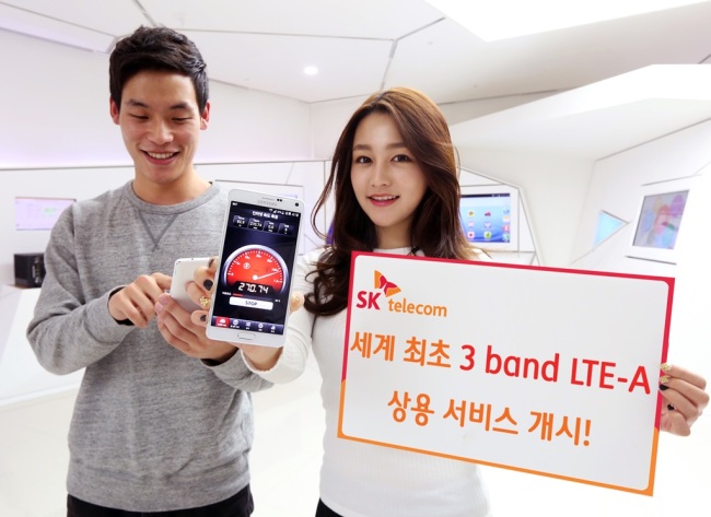 SK Telecom employees pose with a smartphone and a placard introducing the company’s tri-band LTE-A service. SK Telecom