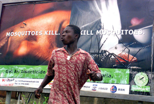 An unidentified man runs past a billboard showing the dangers of malaria in Lagos, Nigeria.   AP
An unidentified man runs past a billboard showing the dangers of malaria in Lagos, Nigeria.   AP