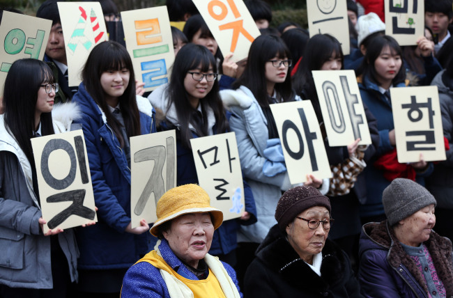 <YONHAP PHOTO-1170> '잊지 말아야할 아픈 역사' (서울=연합뉴스) 이지은 기자 = 성탄 전날인 24일 오후 서울 종로구 중학동 주한일본대사관 앞에서 열린 위안부 문제 해결을 위한 정기 수요집회에서 이용수, 김복동, 길원옥 할머니 뒤로 학생들이 손팻말을 들고 있다. 2014.12.24 jieunlee@yna.co.kr/2014-12-24 13:26:51/ <저작권자 ⓒ 1980-2014 ㈜연합뉴스. 무단 전재 재배포 금지.>
Victims of Japan’s sexual slavery during World War II and students participate in a weekly protest in front of the Japanese Embassy in downtown Seoul on Dec. 24.   Yonhap