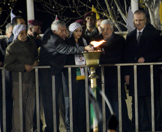 Palestinian President Mahmoud Abbas lights a torch at a rally celebrating the 50th anniversary of the establishment of the Fatah Party in Ramallah, West Bank, Wednesday.   UPI-Yonhap