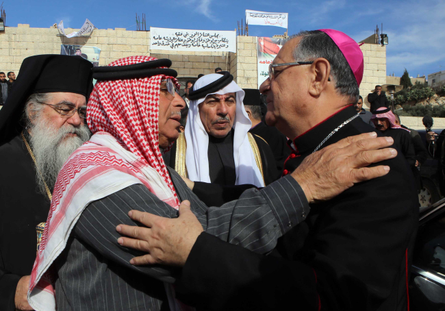 Safi Yousef al-Kaseasbeh (center left), the father of Jordanian pilot 1st Lt. Mu’ath al-Kaseasbeh, and Latin Patriarch of Jerusalem, Fouad Twal, greet each other, as the patriarch and other Christian clergymen visit the al-Kaseasbeh family to show their support and solidarity, in Karak, Jordan, Saturday.    AP-Yonhap