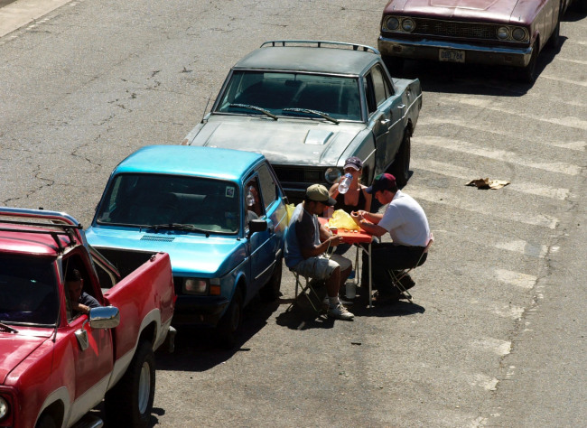 Venezuelans have lunch while waiting in a long line to buy gasoline in Caracas, Venezuela.   Bloomberg