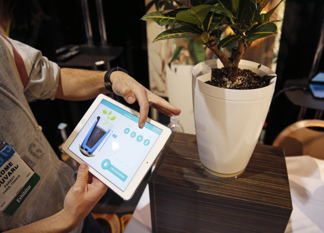A man demonstrates the Parrot Pot at CES Unveiled, a media preview event for the International CES, in Las Vegas on Sunday. The pot is linked to mobile devices and will automatically water the plant.    AP-Yonhap