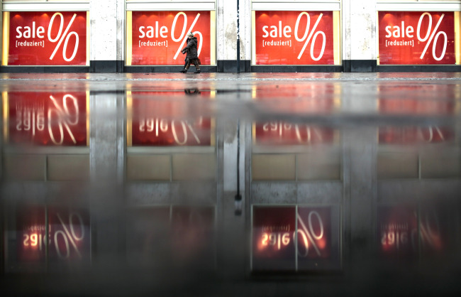 Pedestrians walk in front of sales posters displayed at a department store in Berlin.   AP-Yonhap