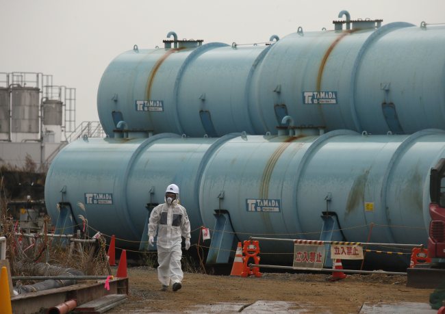 A worker walks past storage tanks of radioactive contaminated water at the tsunami-crippled Fukushima Daiichi Nuclear Power Plant.   EPA-Yonhap