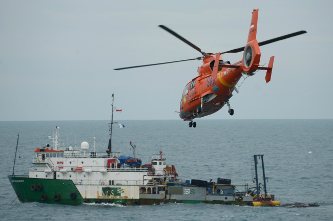A national search and rescue helicopter flies over Geo Survey ship where the tail of AirAsia Flight QZ8501 was found, in Java Sea, Indonesia, Thursday.    Xinhua-Yonhap